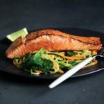 grilled fish, cooked vegetables, and fork on plate