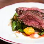 medium rare sliced steak in white ceramic plate